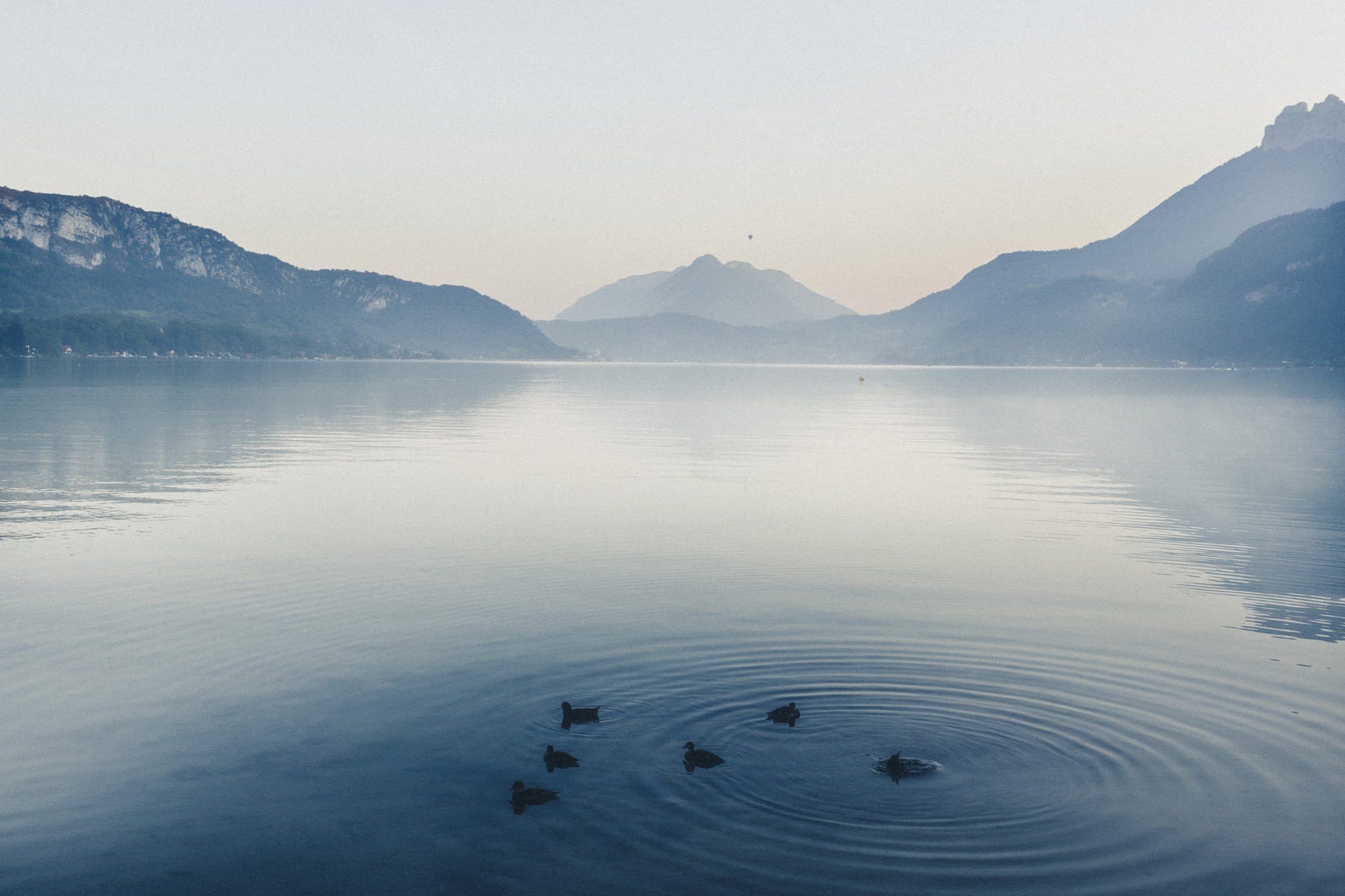 Reliefs de montagne dans la brume au-dessus d'un lac au petit jour.